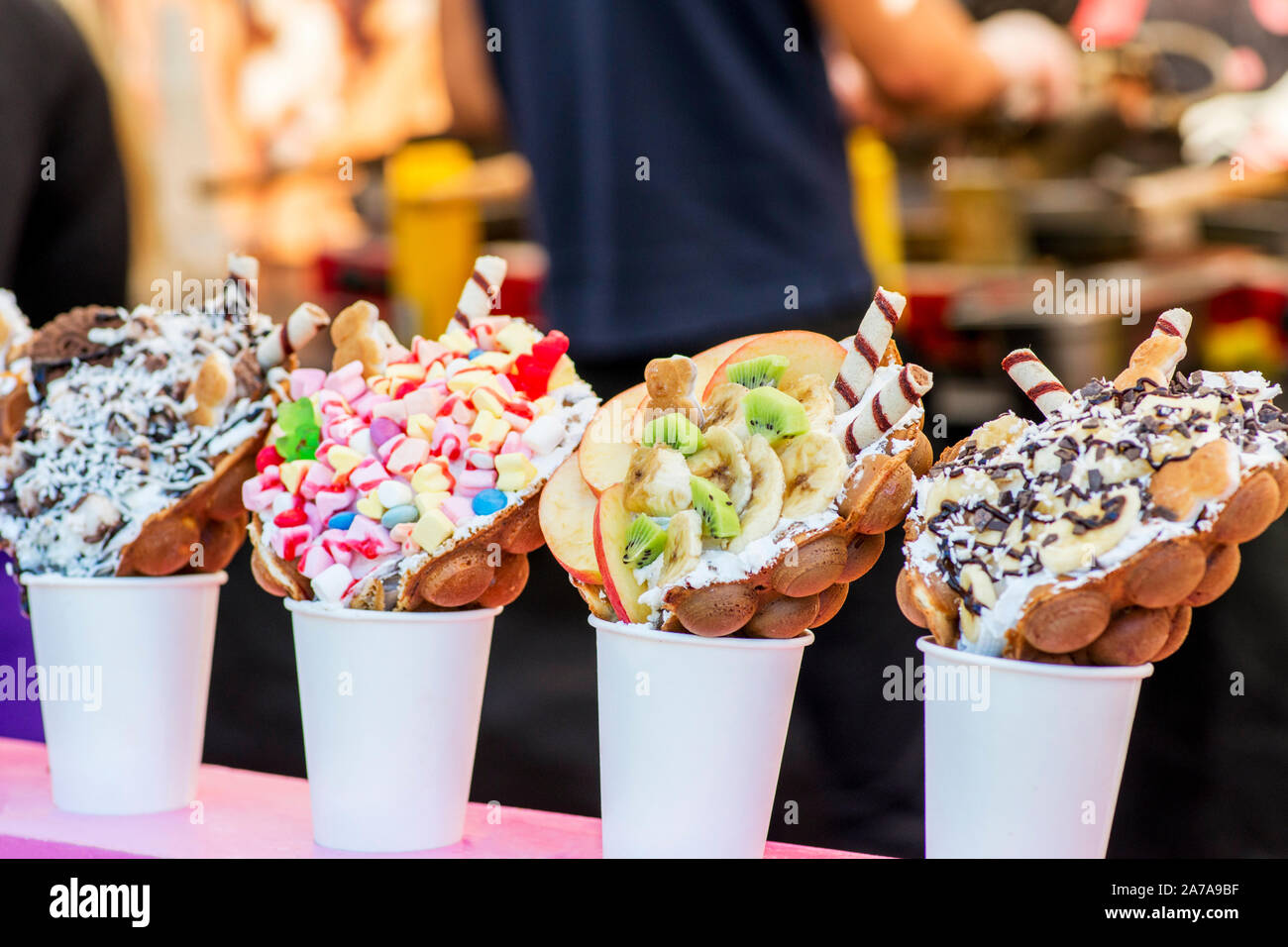 Bubble cialde con lamponi, cioccolato e marshmallow bianco in bicchieri di carta sono venduti su cucina aperta food festival evento. Cucina di strada in stallo alimentare Foto Stock