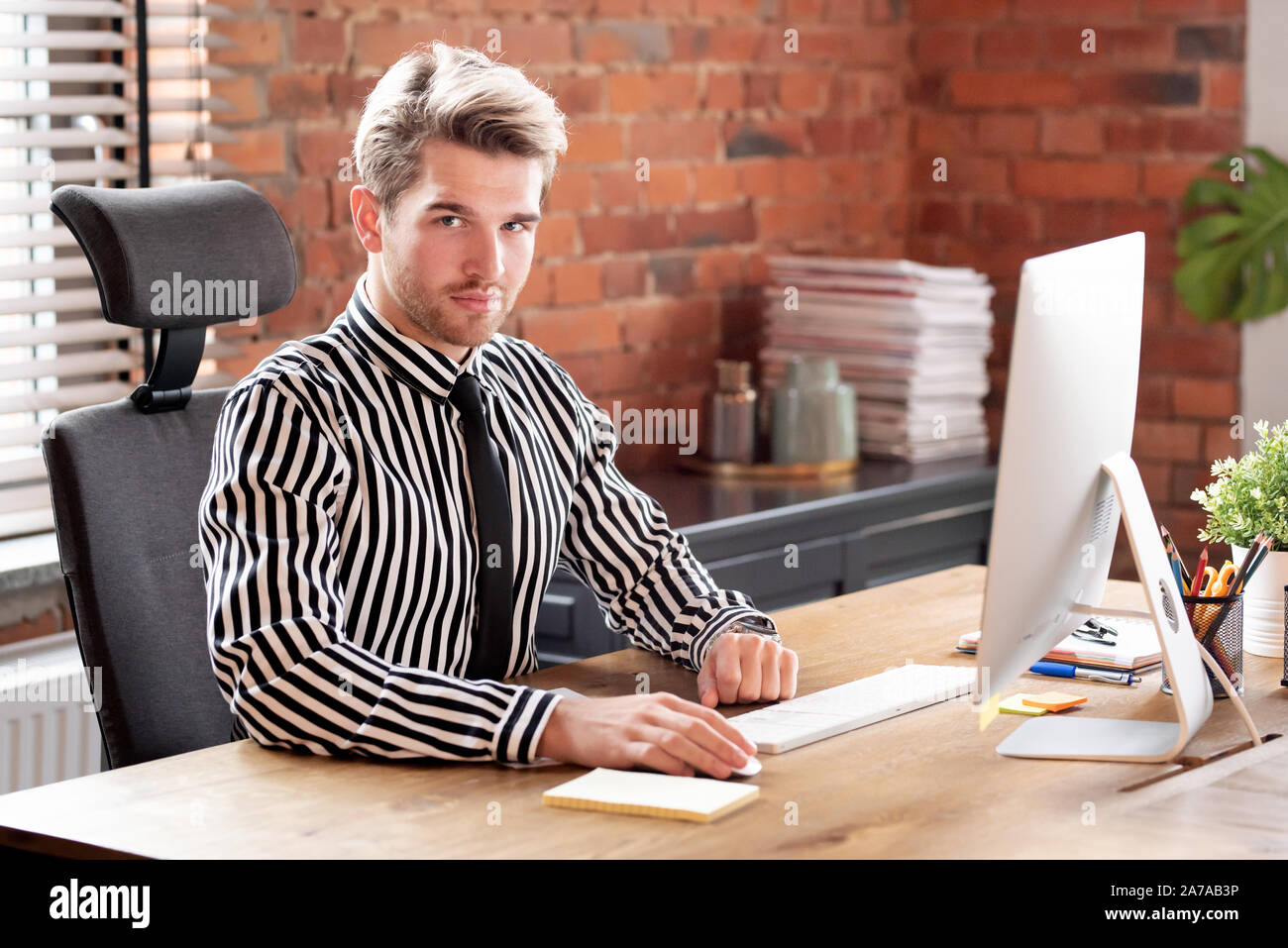 Imprenditore lavora in ufficio. Bello dipendente utilizzando computer desktop Foto Stock