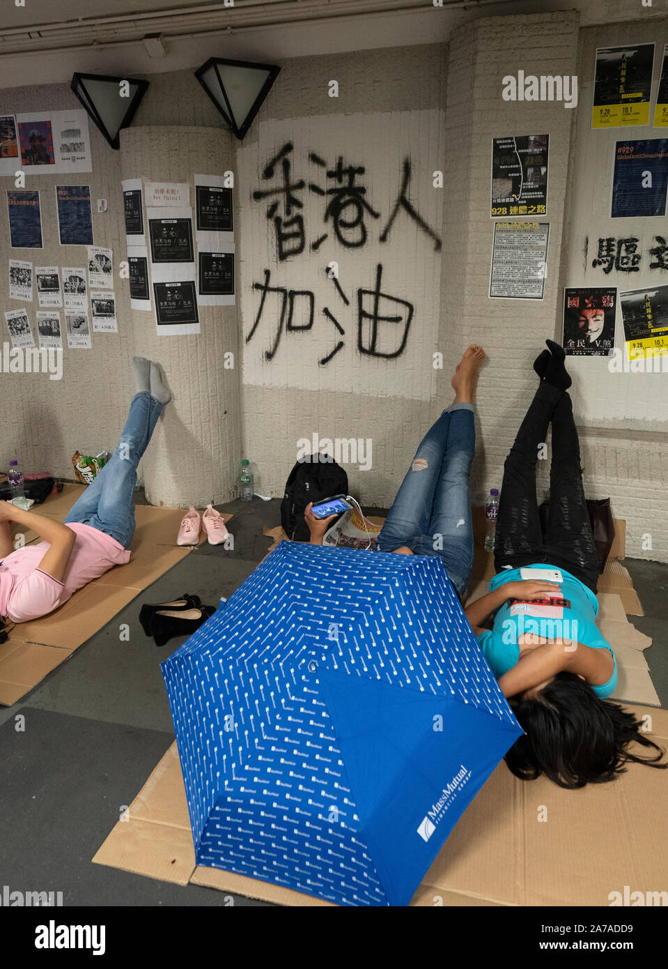 Pro democrazia graffiti spruzzato sul sottopassaggio pedonale con collaboratori domestici a rilassante weekend al traghetto Star in centro a Hong Kong. Foto Stock