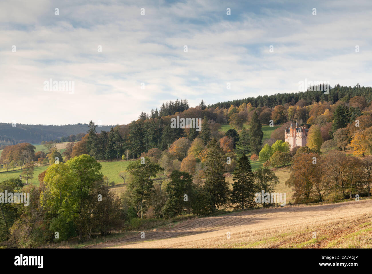 Castello di Craigievar sorge sul pendio di una collina in inizio di mattina di sole, circondato da alberi in un colorato fogliame di autunno Foto Stock