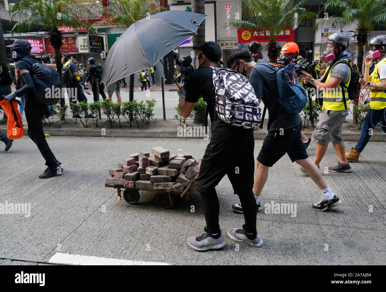 Pro-democrazia manifestanti mattoni in movimento sul carrello verso le linee della polizia di Hong Kong Foto Stock