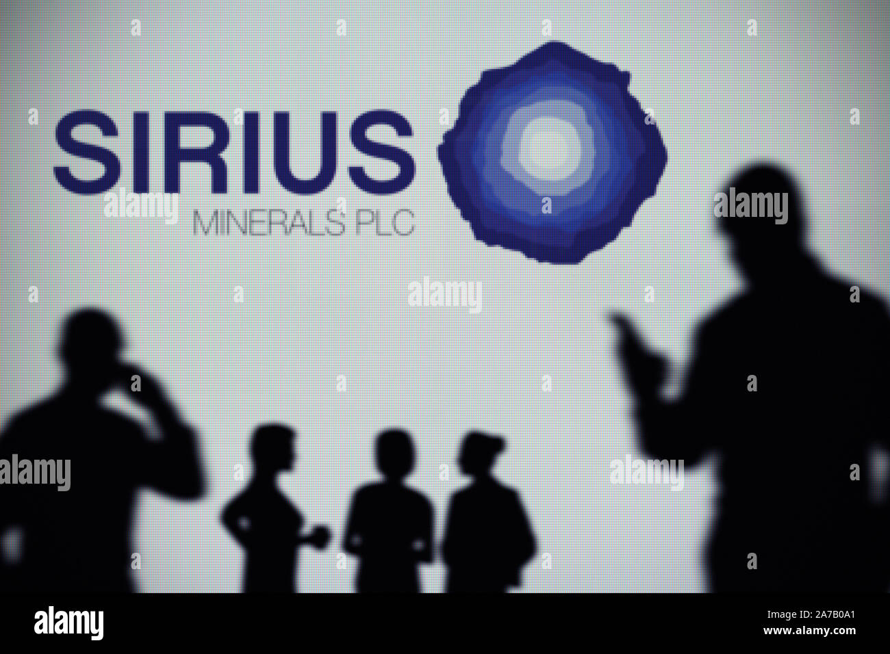Sirius minerali logo è visibile su uno schermo a LED in background mentre si profila una persona utilizza uno smartphone (solo uso editoriale) Foto Stock