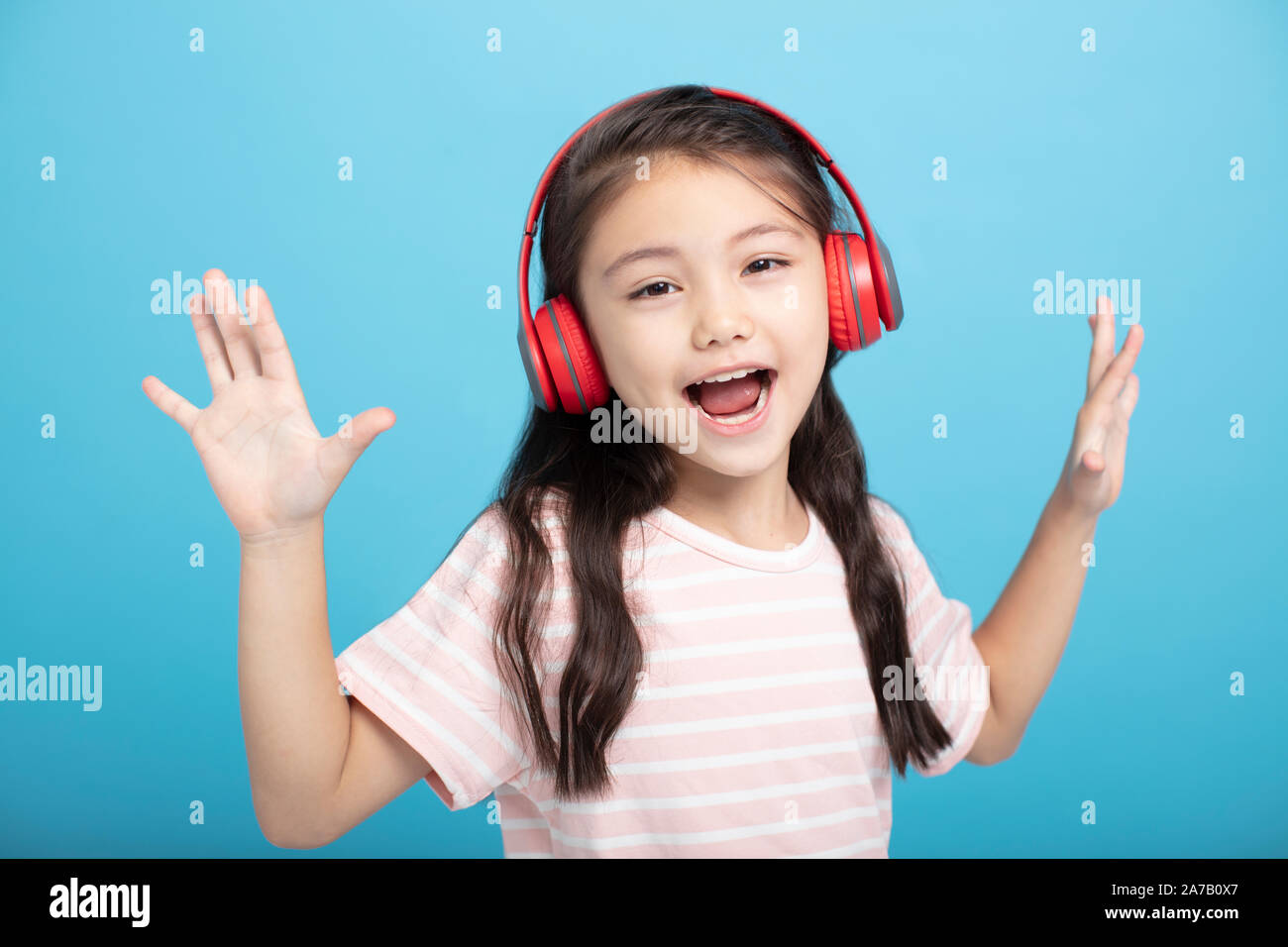 Felice bambina con ascolto in cuffia e cantare il brano Foto Stock