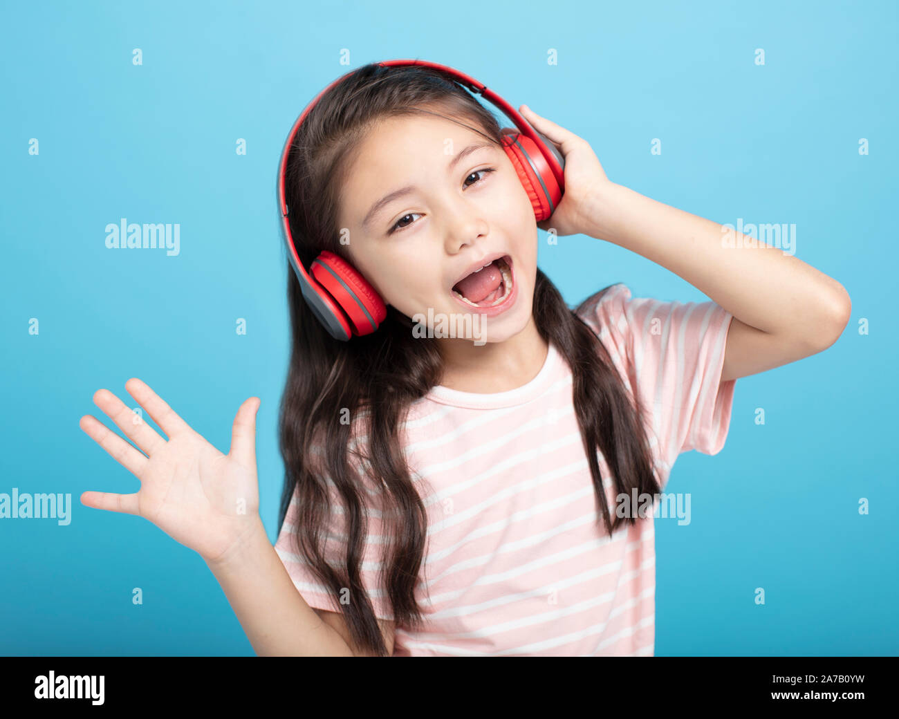 Felice bambina con ascolto in cuffia e cantare il brano Foto Stock