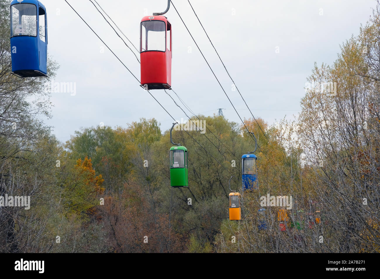 Funivia oltre il parco d'autunno. Doppia funivia colorate cabine. Strada di sospensione per il trasporto passeggeri. Foto Stock