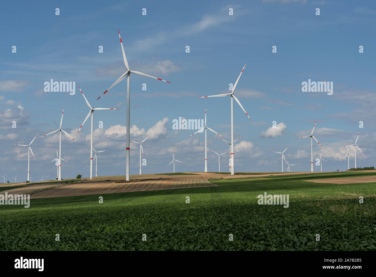 Le turbine eoliche sui campi sotto un cielo blu con alcune nuvole Foto Stock