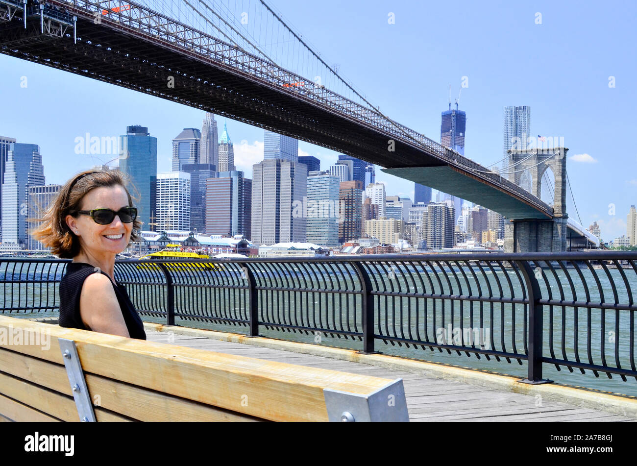 Donna sul banco sotto il ponte di Brooklyn, Brooklyn, DUMBO, traghetto Empire-Fulton parco statale, East River, Manhattan, New York Foto Stock