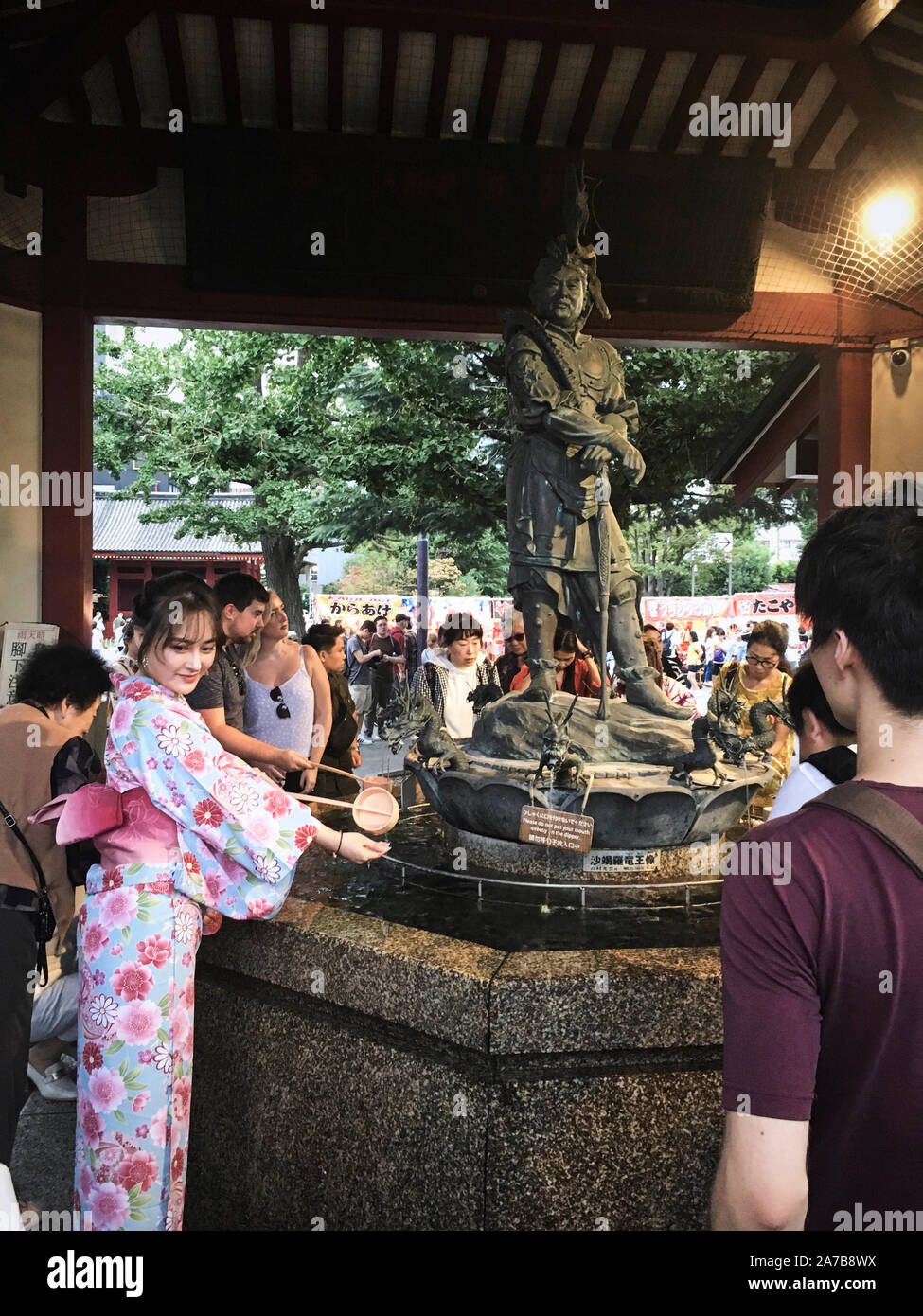 Una donna in kimono pulizia prima di entrare nel tempio di Sensoji al Demboin Giardino del Tempio in Alaska, Tokyo. Foto Stock