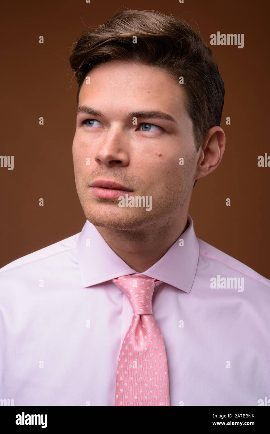 Studio shot del giovane imprenditore bello con maglia rosa Foto Stock
