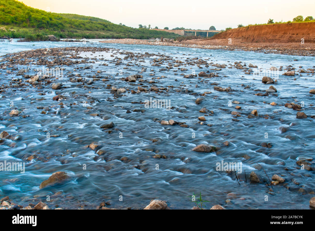 Fiume che scorre acqua con il riflesso del cielo blu prese con una lenta velocità di otturatore. Foto Stock
