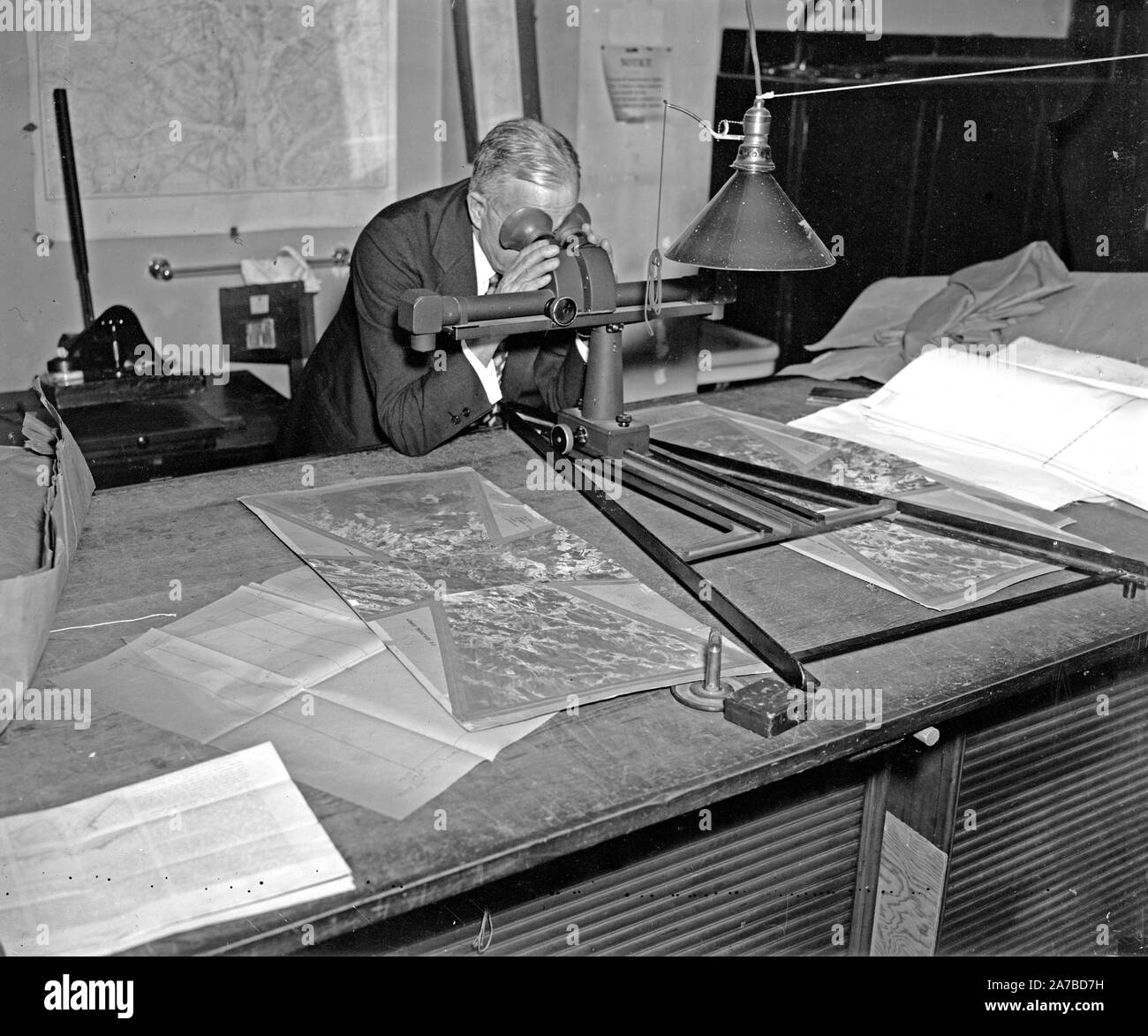 Geological Survey. Washington, 13 marzo. Albert Pike utilizzando uno stereoscopio su una coppia di fotografie per portare fuori la valvola di sfiato e di individuare gli oggetti di una mappa ca. 1937 Foto Stock