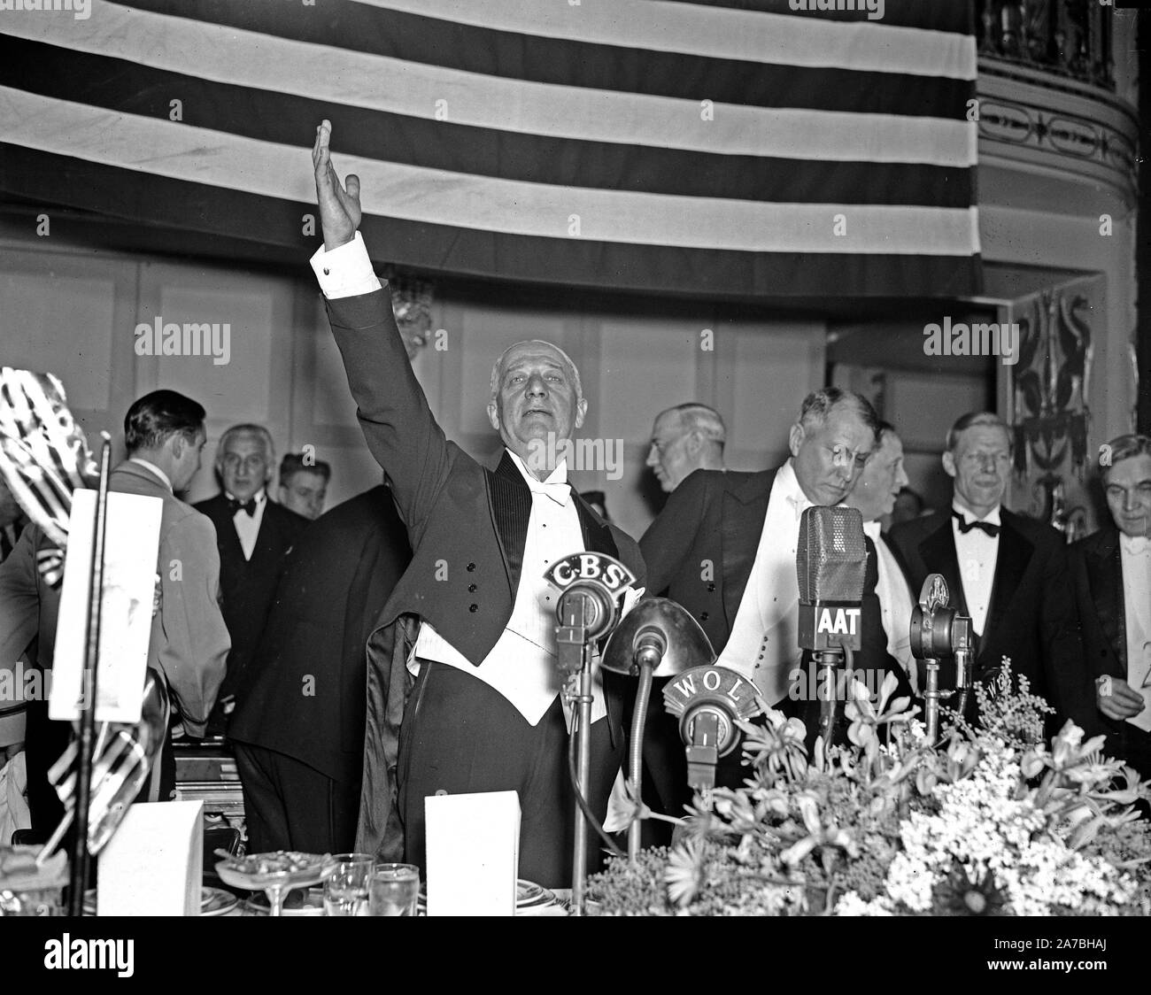 Uomo in smoking in piedi di fronte a CBS radio microfono, mano alzata ca. 1936 Foto Stock
