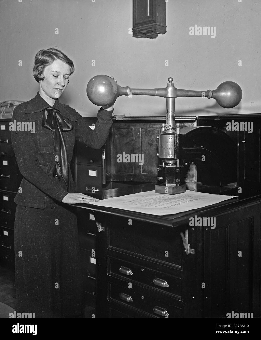 Donna dispositivo dimostrando che impressiona il grande sigillo degli Stati Uniti su alcuni documenti ufficiali ca. 1935 Foto Stock