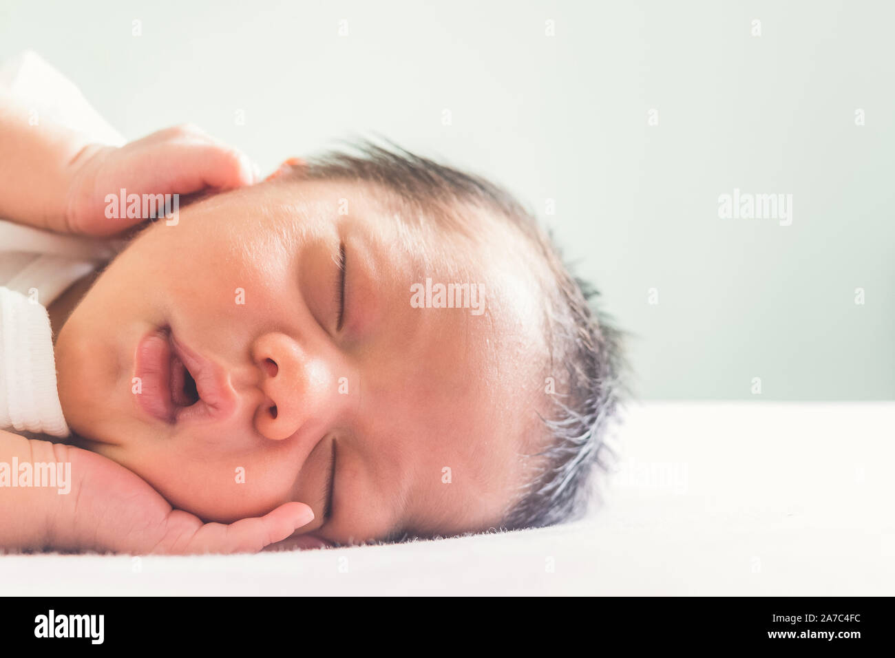 Carino neonato Bambino addormentato sul letto in camera dei bambini alla mattina il tempo con copia spazio. famiglia, sano, vita e concetto di relazione Foto Stock