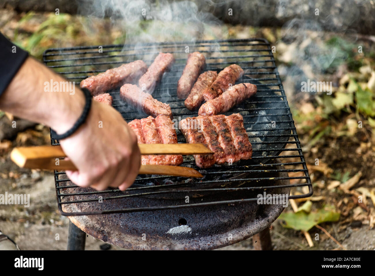 Cucina balcanica Cevapi di maiale e grigliate di carni macinate, sulla griglia improvvisata Foto Stock