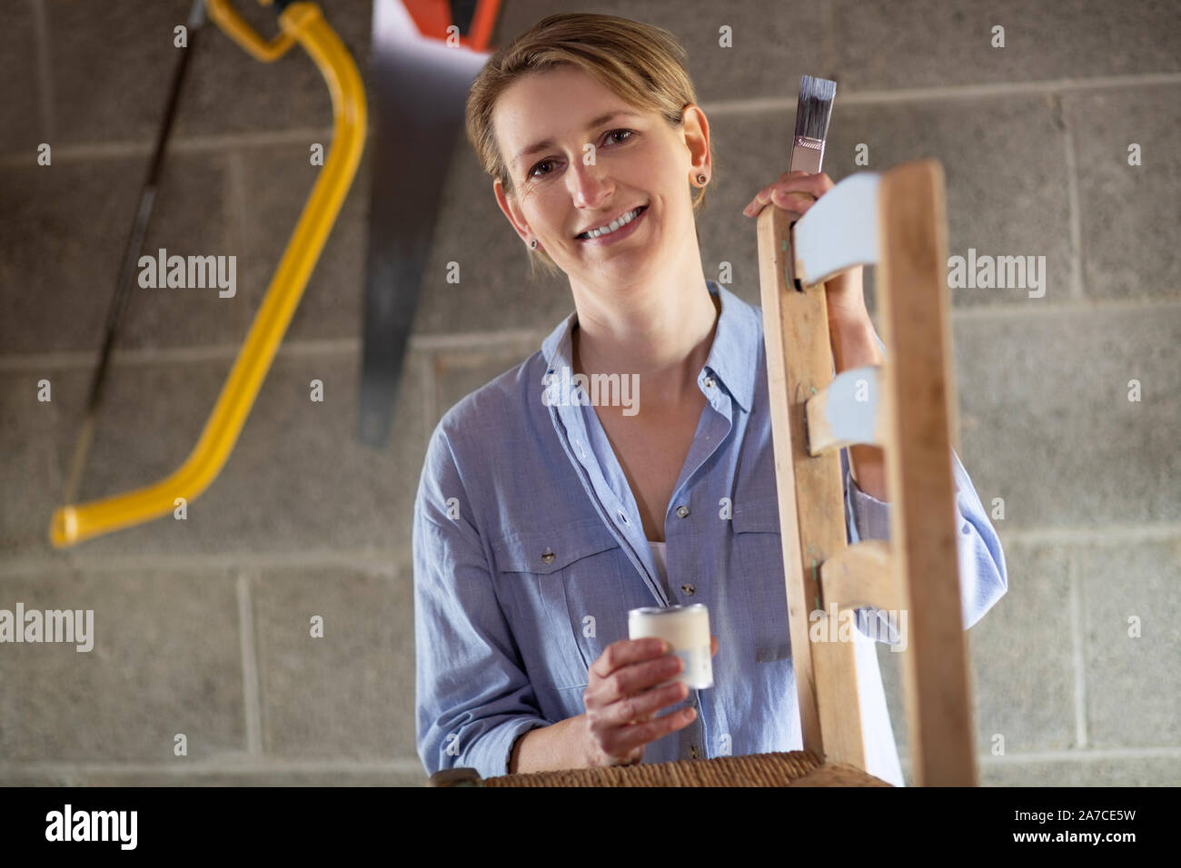 Ritratto di donna matura Upcycling mobili in officina a casa pittura sedia in legno Foto Stock