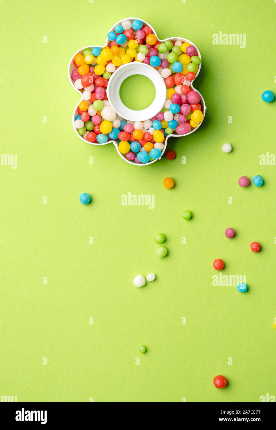 Layout creativi di forma di fiore con caramelle colorate su sfondo verde e il luogo per il testo Foto Stock