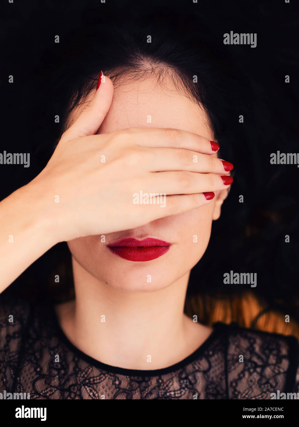 Giovane e bella donna che copre gli occhi con la mano Foto Stock