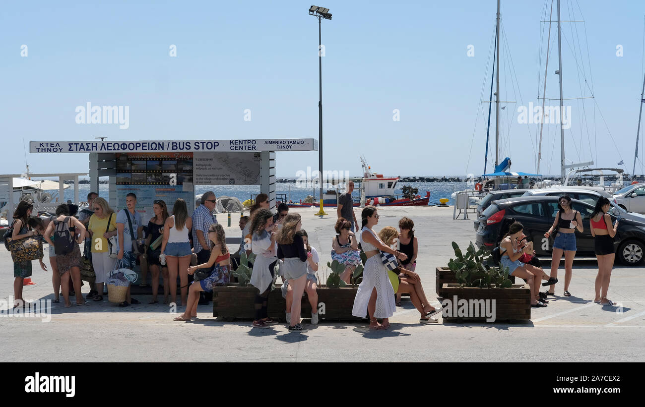 Coda di turisti in corrispondenza di una fermata bus sull'isola di Tinos, Grecia. Foto Stock