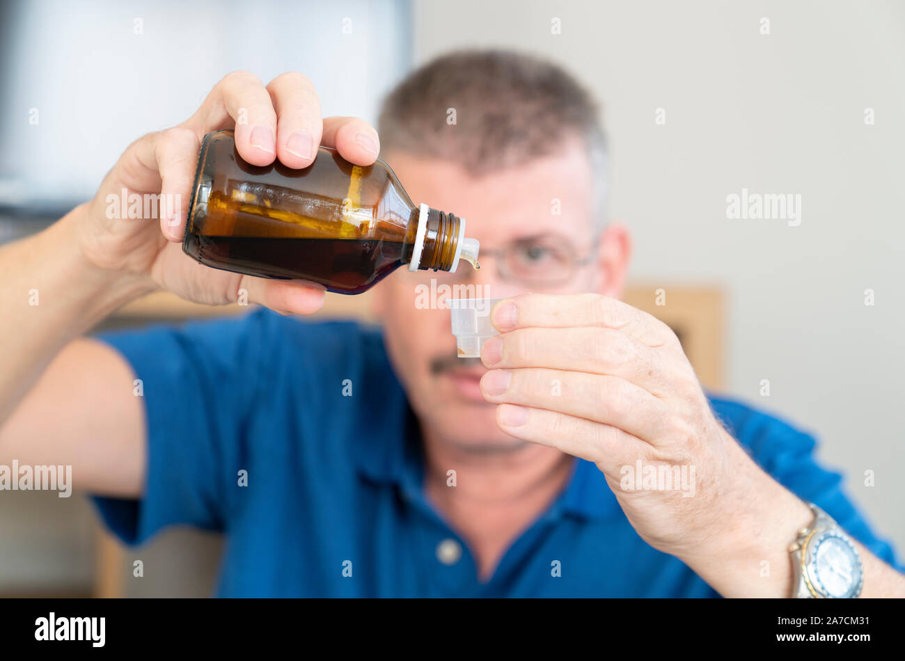 Uomo di medicina di colata in una coppa measurning Foto Stock