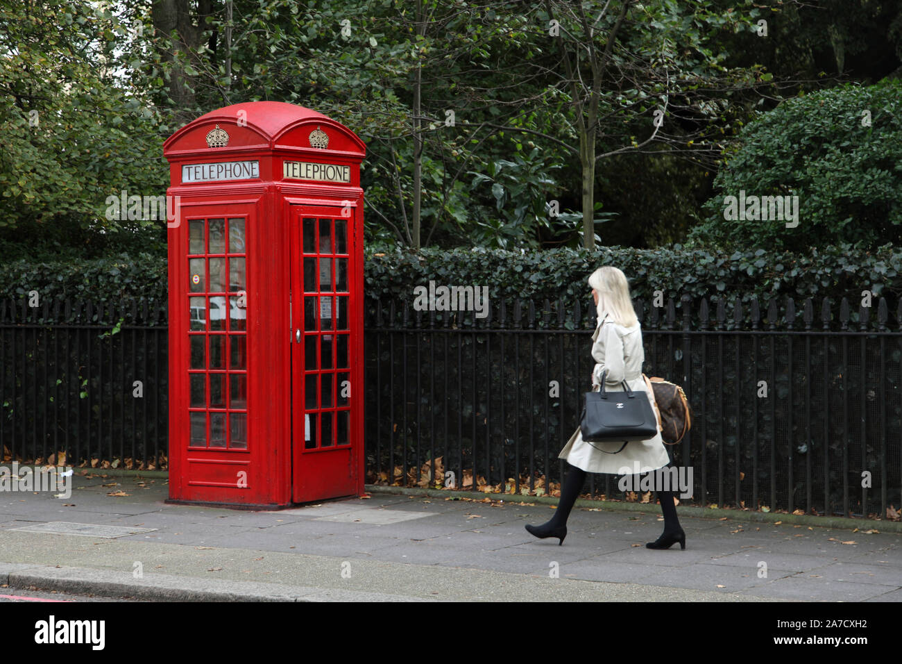 Una donna passa davanti a una scatola telefonica rossa K2 a Londra, Inghilterra, Regno Unito Foto Stock