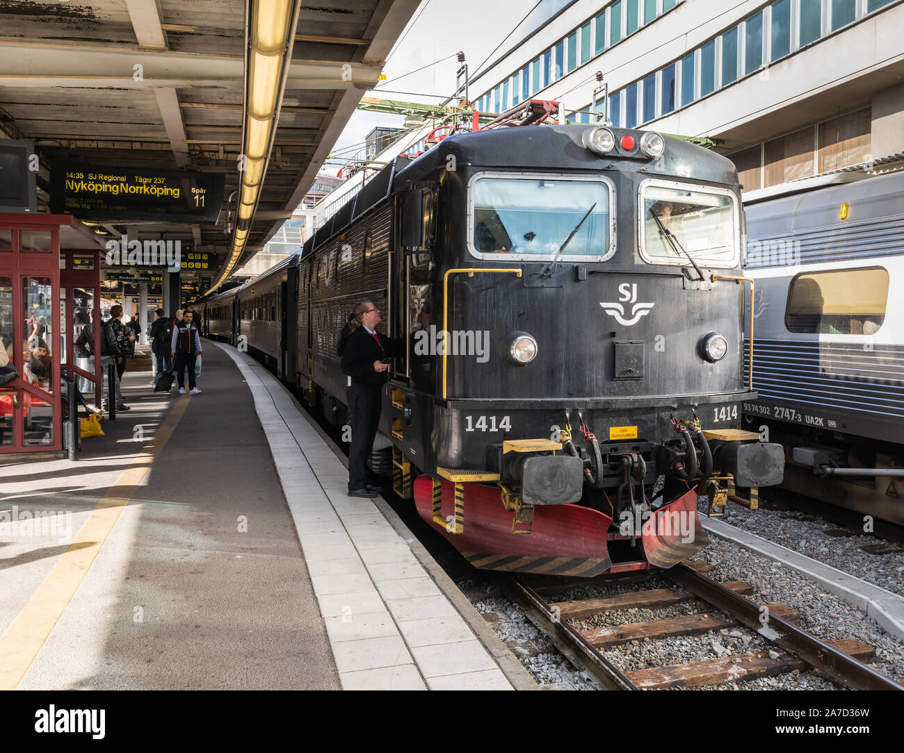 Stoccolma, Svezia: presso la stazione centrale di un membro del personale di stazione di colloqui per il conducente della locomotiva elettrica voce un treno locale a Norrköping. Foto Stock