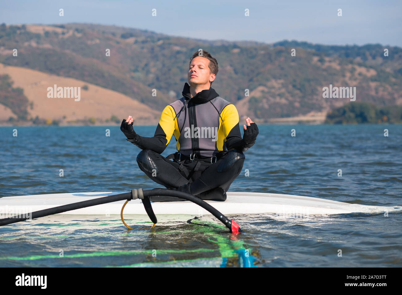 Windsurf fare yoga mentre è seduto sulla tavola da surf. Lo sport e il relax del concetto. Foto Stock