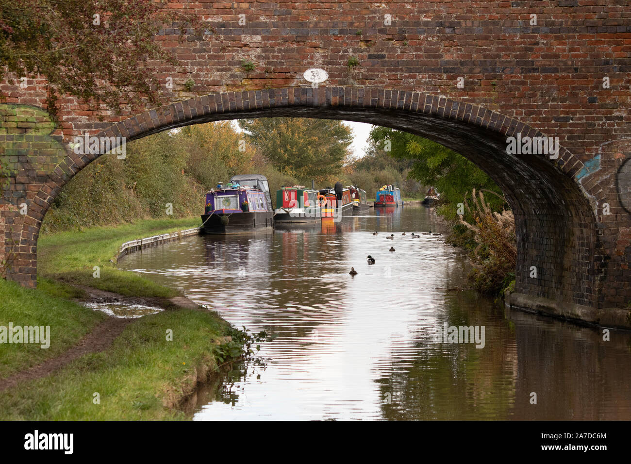 Una vista attraverso uno dei ponti sul canale lungo la Coventry canal vicino Hartshill nel Warwickshire Foto Stock