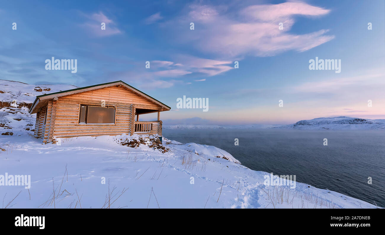 Una casa in legno, il mare di Barents al tramonto in Teriberka, Regione di Murmansk, la penisola di Kola. La Russia. Foto Stock