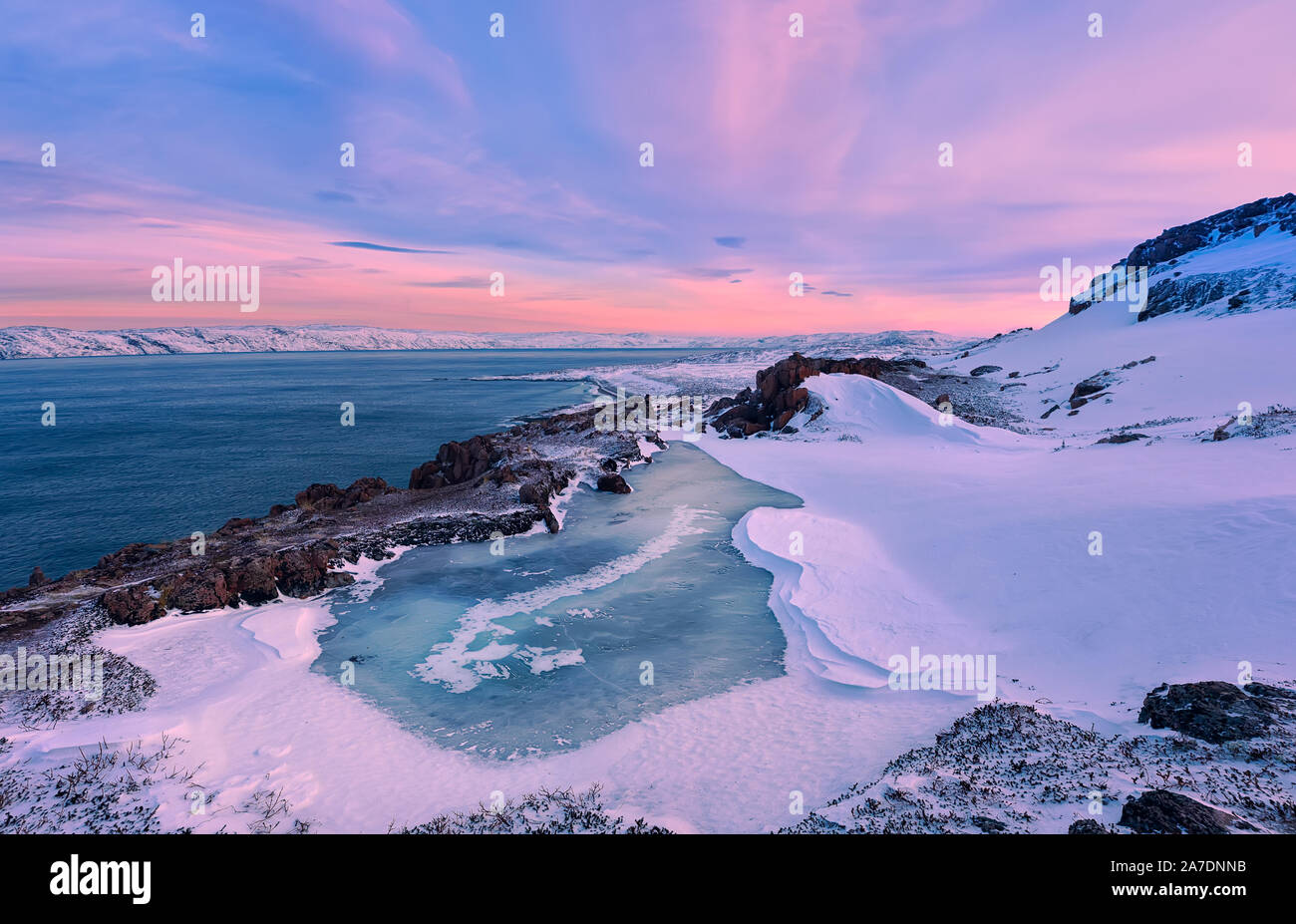 Un piccolo lago ghiacciato e il Mare di Barents costa al tramonto. Teriberka, Regione di Murmansk, la penisola di Kola. La Russia. Il focus principale sul lago ghiacciato. Foto Stock