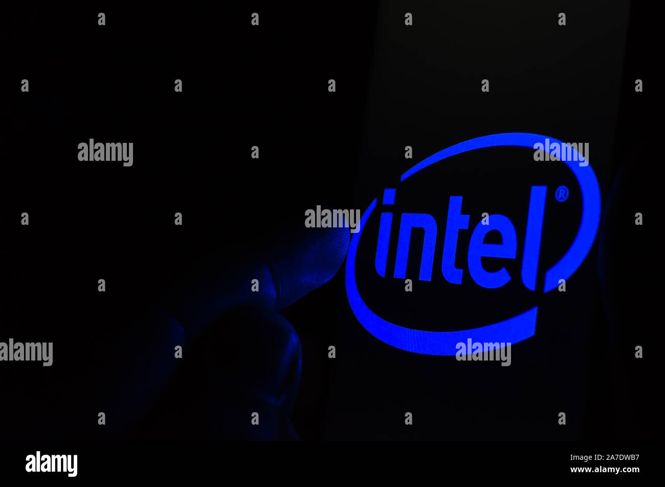 Logo Intel su una schermata dello smartphone in una stanza buia e un dito di toccarlo. Foto Stock