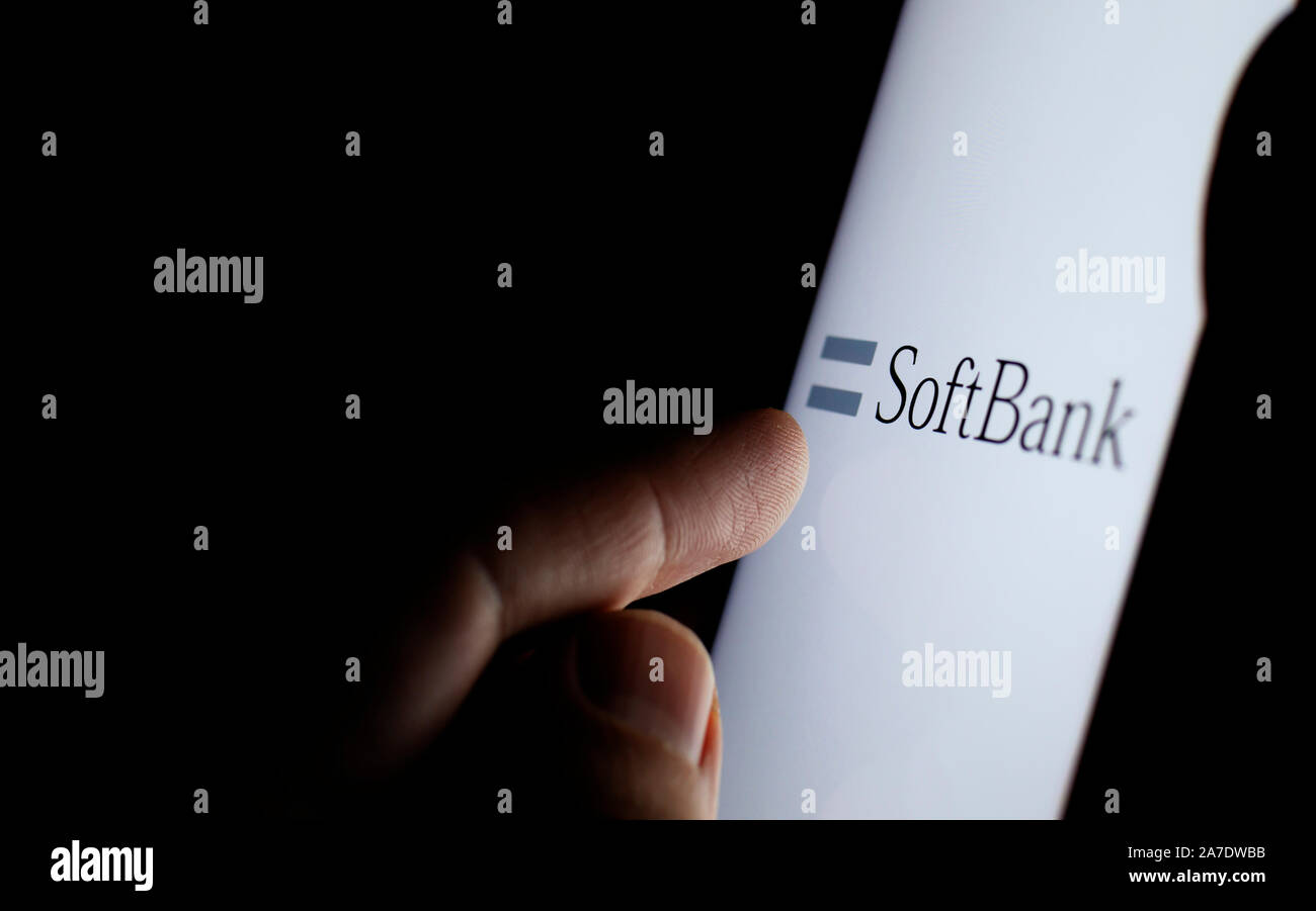 Softbank logo su una schermata dello smartphone in una stanza buia e un dito di toccarlo. Foto Stock