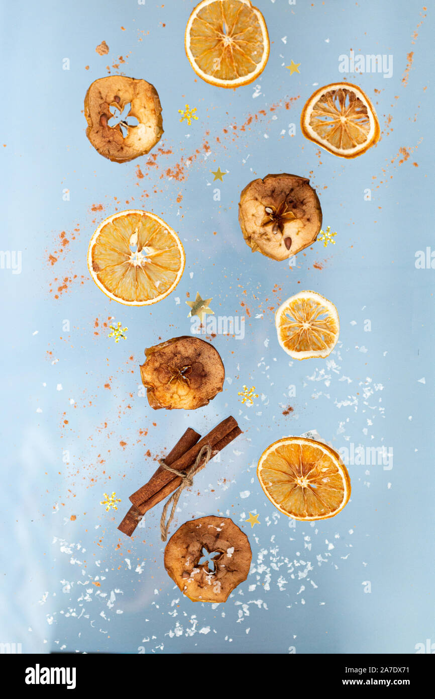 Biscotti allo zenzero secco con mele e arance fette e la stecca di cannella sono battenti su uno sfondo blu. Levitazione di cibo. Concetto di natale Foto Stock