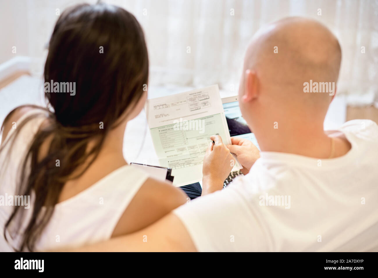 Coppia giovane sul divano con il computer portatile e contare la fattura per il pagamento. Il concetto di servizi di pubblica utilità, debito, di persone e di credito. Concetto di famiglia, bilancio familiare. Foto Stock