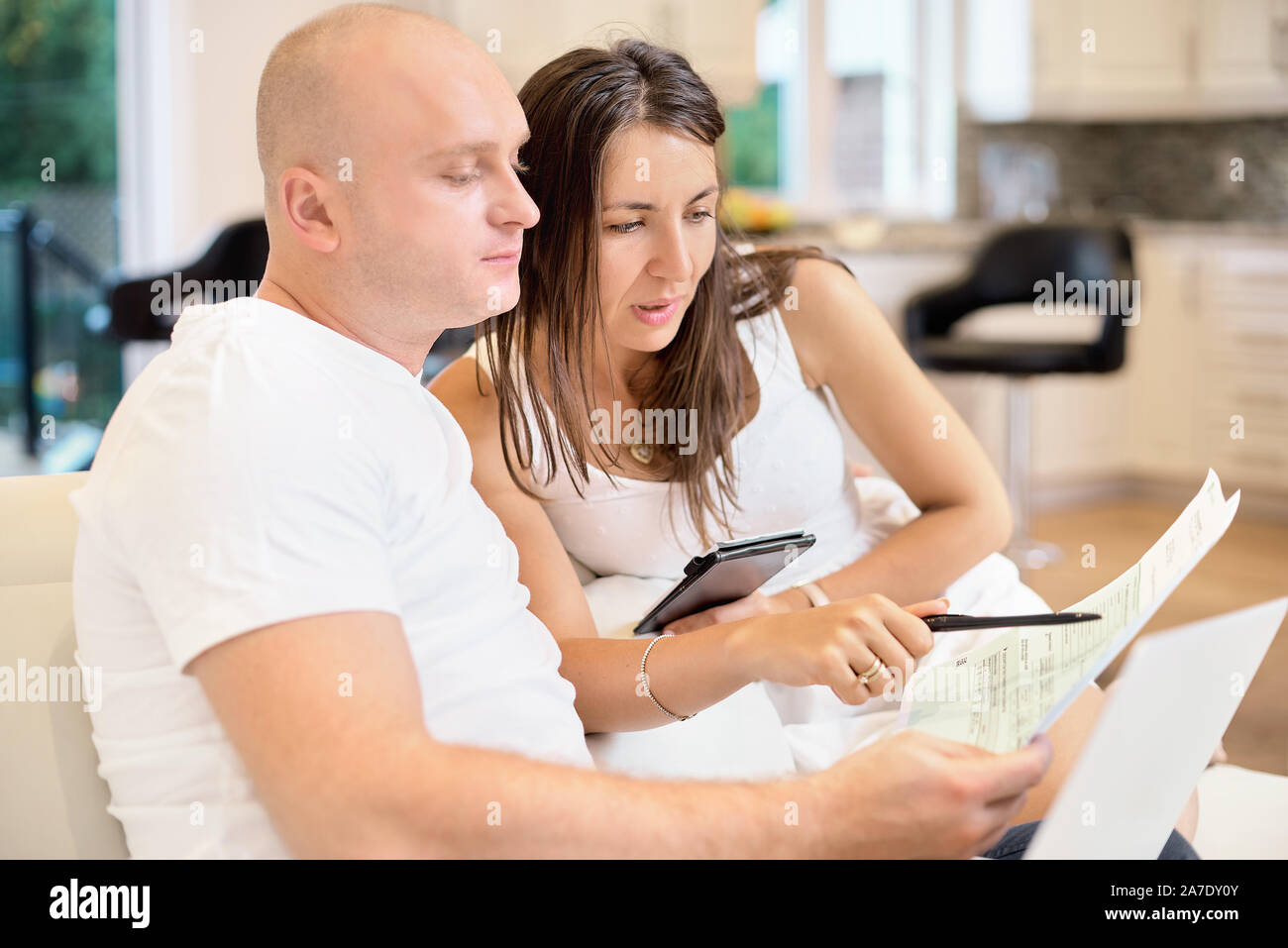 Coppia giovane sul divano con il computer portatile e contare la fattura per il pagamento. Il concetto di servizi di pubblica utilità, debito, di persone e di credito. Concetto di famiglia, bilancio familiare. Foto Stock