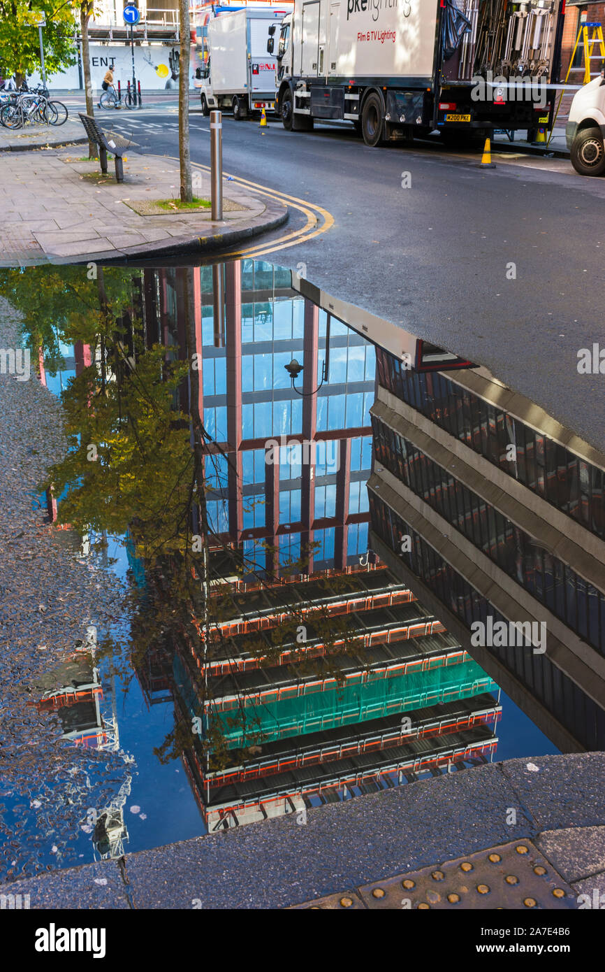 Parte del circolo di sviluppo quadrato (in costruzione, Ott 2019), che si riflette in una pozzanghera, Chester Street, Off Oxford Road, Manchester, Inghilterra, Regno Unito Foto Stock