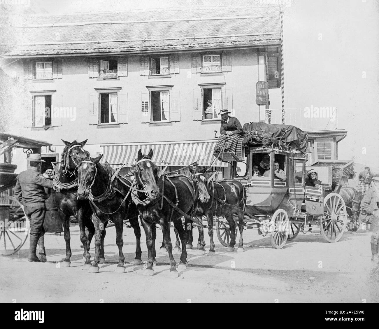 Un inizio di vintage fotografia in bianco e nero che mostra una fase coach tirato da sei cavalli si prepara a lasciare una piccola città europea con passeggeri a bordo. Le diligenze conducente siede sulla parte superiore con le sue gambe coperti da una coperta. Alcuni passeggeri sono in parte racchiusa del pullman, altri sit in fuori la parte esposta del pullman. Foto Stock