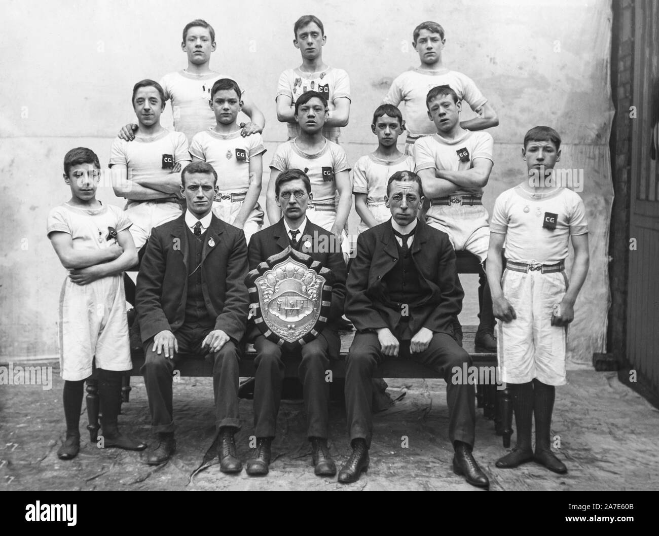 Una vendemmia tardiva precoce Vittoriano Edwardian fotografia in bianco e nero che mostra un gruppo di giovani ragazzo inglese ginnasti che posano per una fotocamera mentre loro coach o manager mostra un grande trofeo scudo. Foto Stock