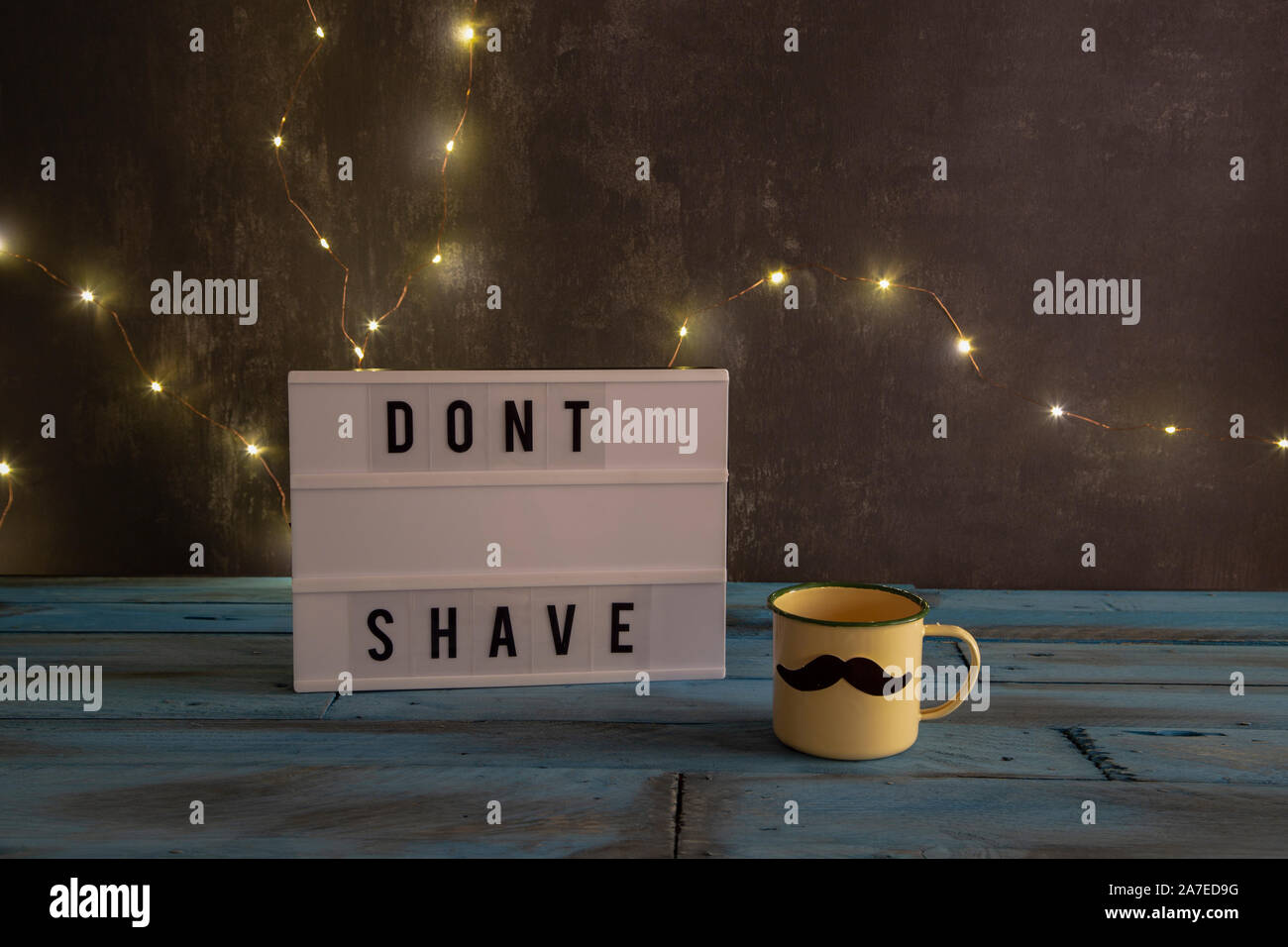 Visual Lightbox con le parole dont radere e una coppa con i baffi sullo sfondo con le luci a led e vintage in legno di colore blu Foto Stock