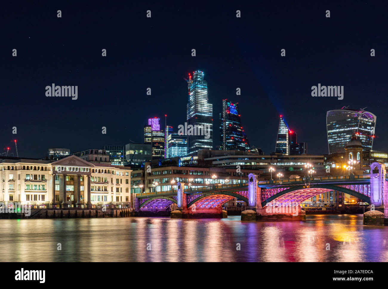 Skyline di Londra di notte illuminata inclusi ponte sul fiume Tamigi e la city di Londra in background Foto Stock