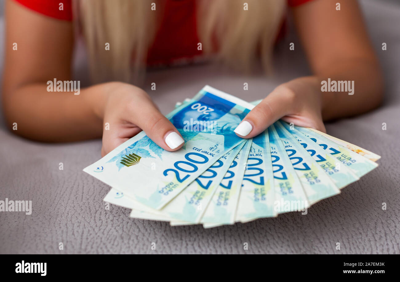 Donna di due mani tenendo una ventola di denaro dei nuovi israeliani sicli. Concetto di finanza,i piani pensionistici e fondi pensione Foto Stock