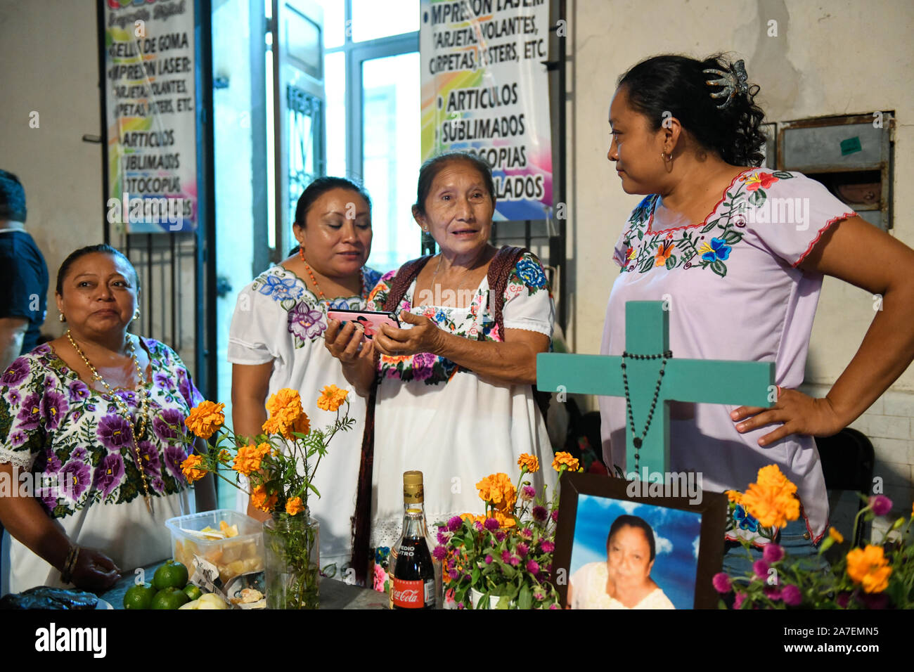 Merida donne con telefono mobile nella parte anteriore del suo altare familiare durante Hanal Pixan che è la celebrazione del Giorno dei morti che ha originato dalla cultura Maya. Merida, Yucatan, Messico . Foto Stock