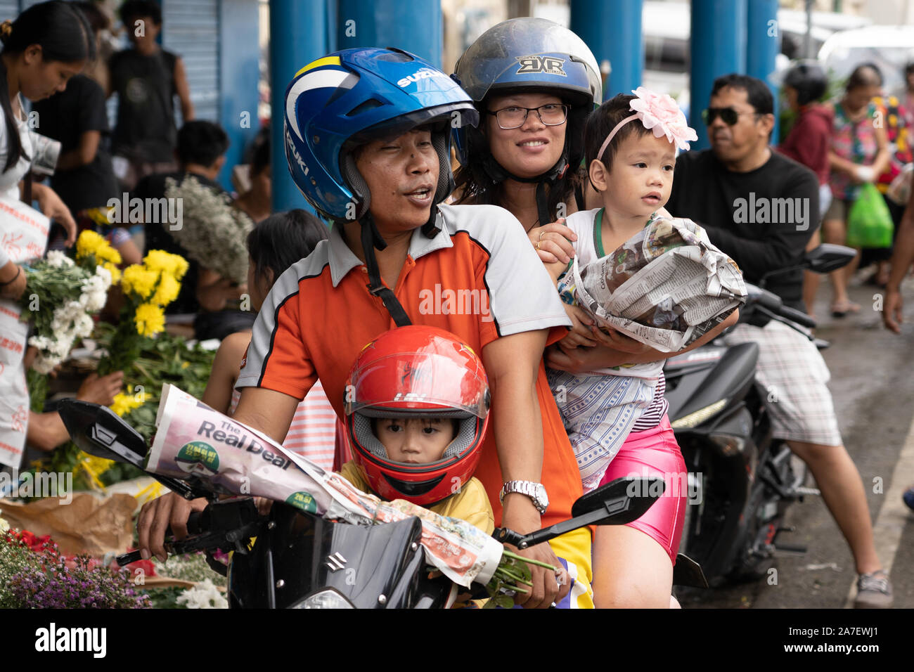 Una famiglia di quattro persone in sella a una motocicletta all'interno di Cebu, Filippine. È abbastanza normale per i bambini più piccoli per essere trasportati in questo modo. Foto Stock