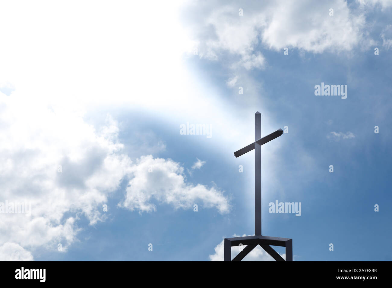 Un crocifisso cristiano in cima ad una chiesa, silhouette da raggi di luce dall'alto. Foto Stock