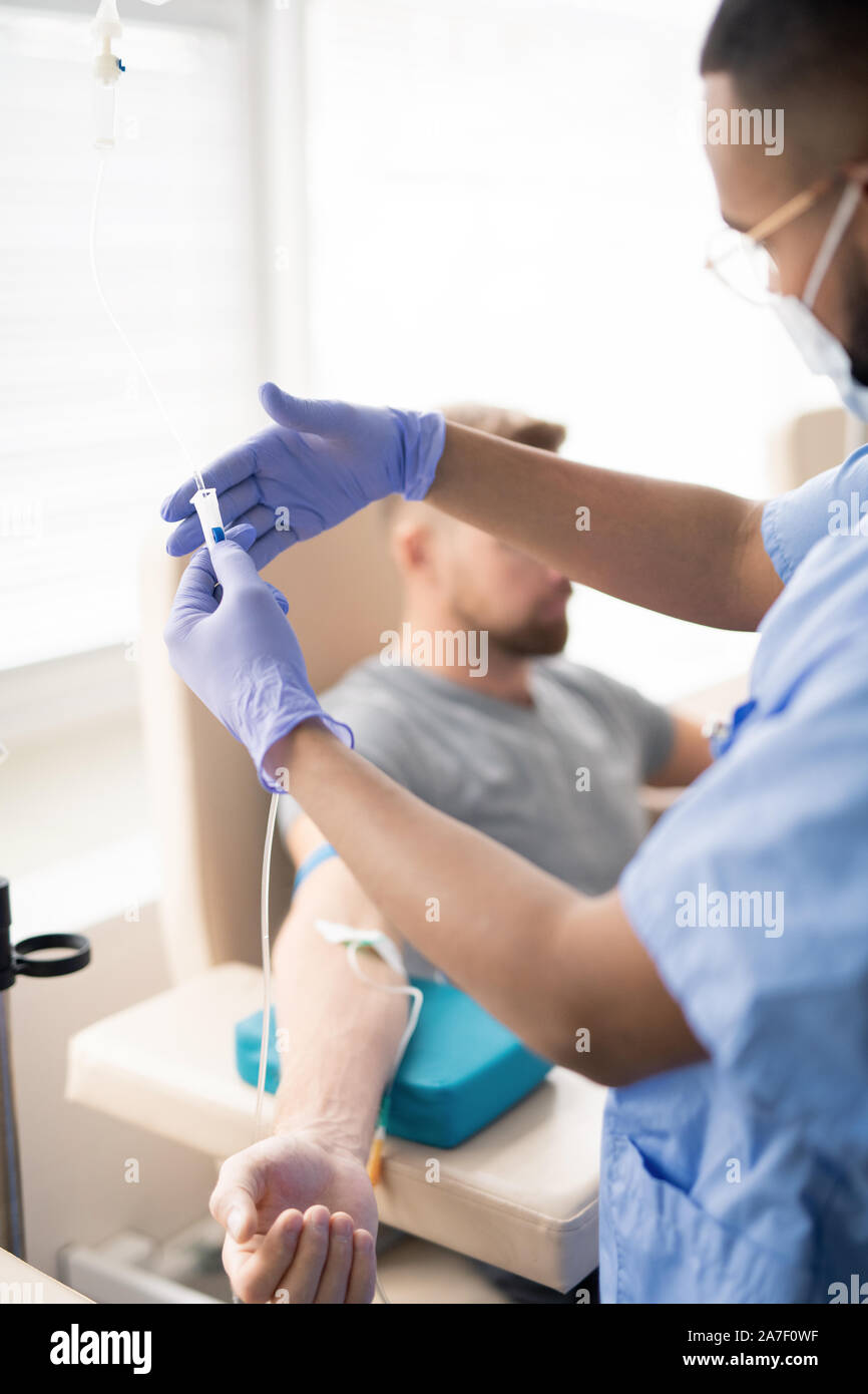 Medico parte di ritegno di un contagocce con la medicina durante il trattamento del paziente Foto Stock