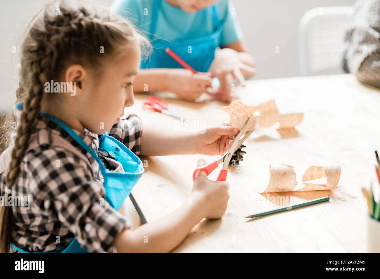 Ragazza carina con forbici seduti a tavola e il taglio della carta i simboli di halloween Foto Stock