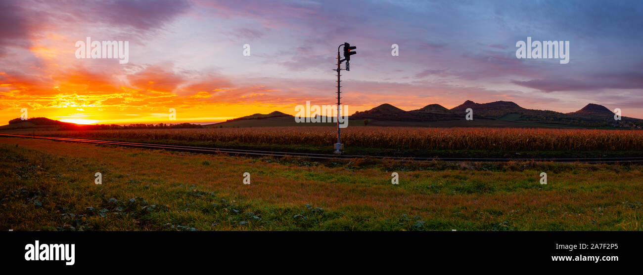 Mattina il treno per l'inferno. Vecchi binari ferroviari in esecuzione attraverso un tratto di campo al paesaggio rurale alle drammatiche sunrise. Foto Stock