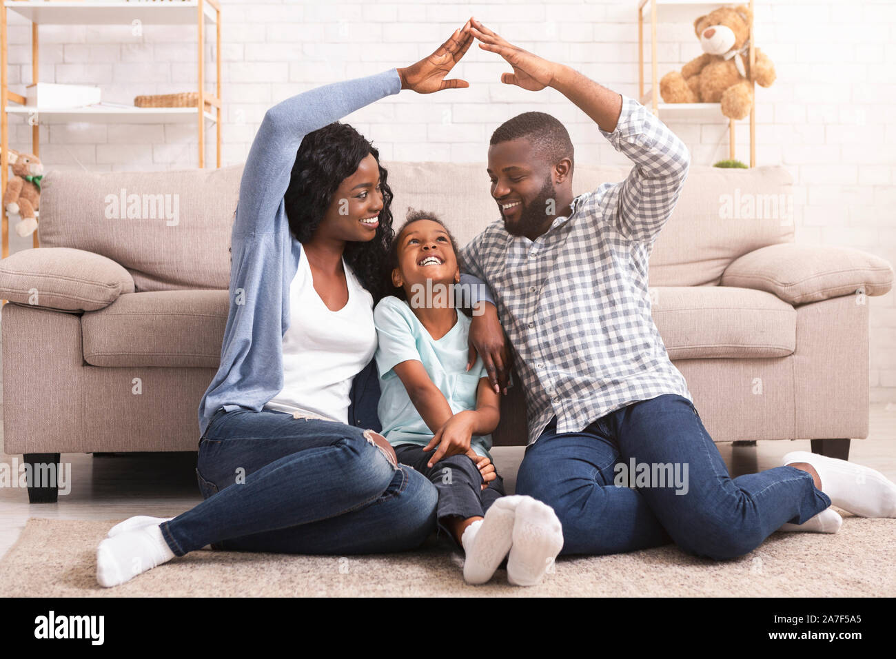 Famiglia nero rendendo tetto simbolico delle mani sopra bambina Foto Stock