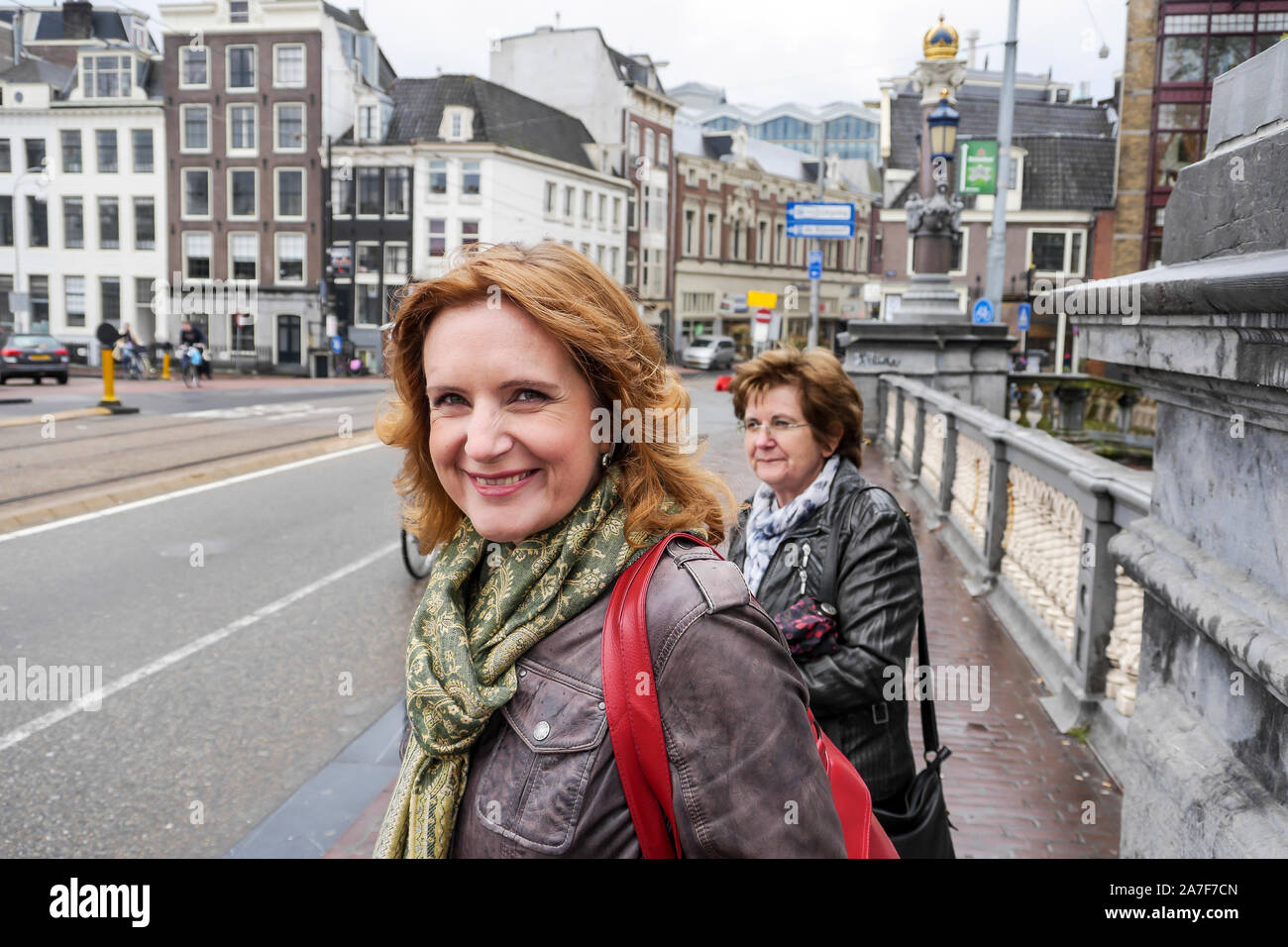 Due donne di mezza età in piedi sul ponte di Amsterdam in attesa di cross street. Medium Shot. Foto Stock