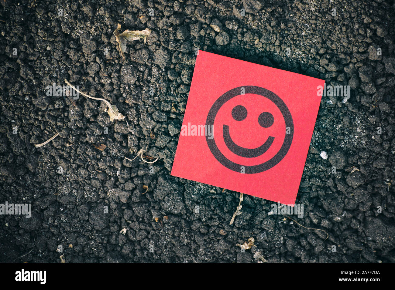 Carta rossa nota con la faccia felice sul terreno dello sfondo. Close up. Foto Stock